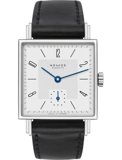 Square stainless steel watch with white dial, blue hands, and black leather strap, NOMOS Glashütte made in Germany.