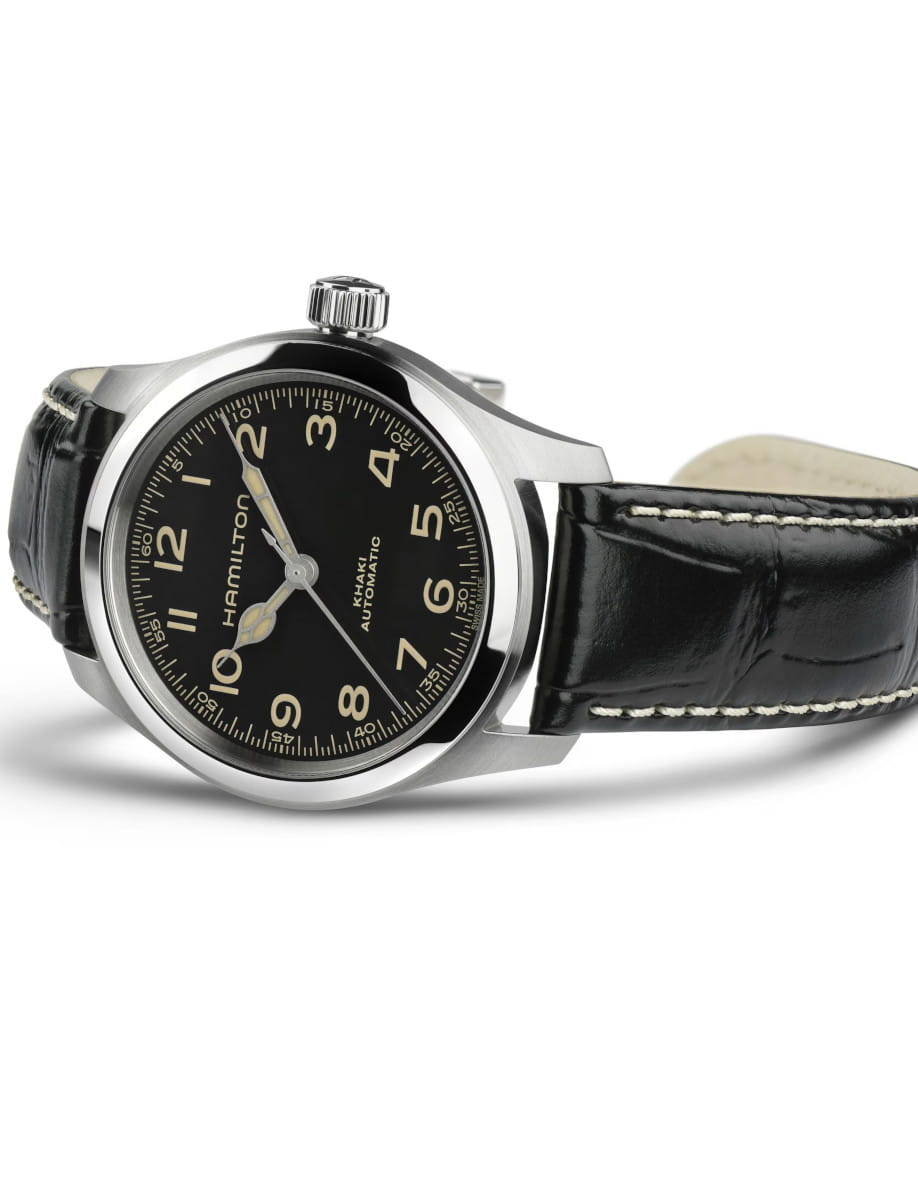 Close-up of a Hamilton Khaki automatic wristwatch with a black dial, white numerals, and a black stitched leather strap on a white background