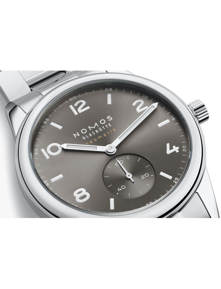 Close-up of a Nomos Glashutte wristwatch with stainless steel case and bracelet, and light grey dial.