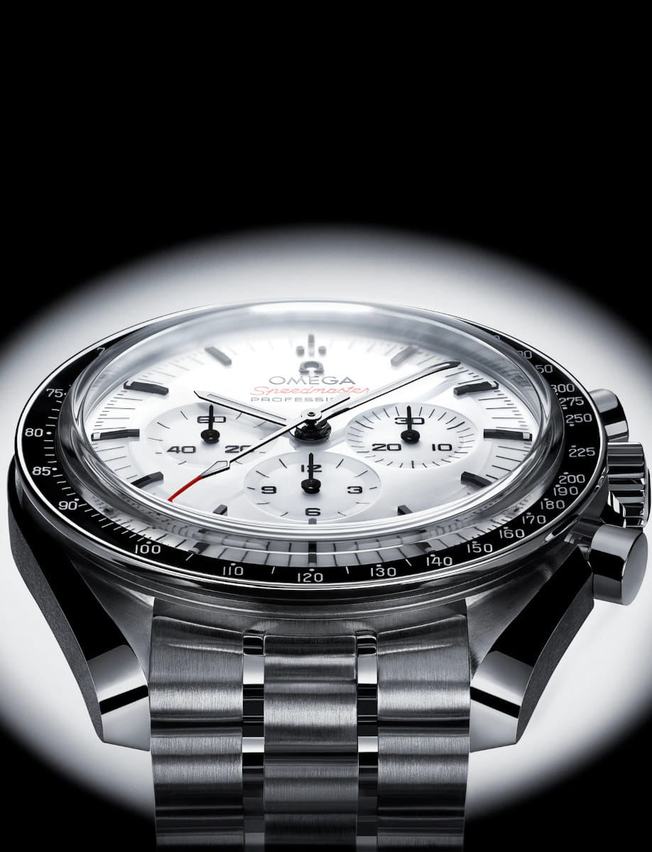 Close-up of a stainless steel Omega Speedmaster Professional chronograph with a white dial and black tachymeter bezel on a metal bracelet.