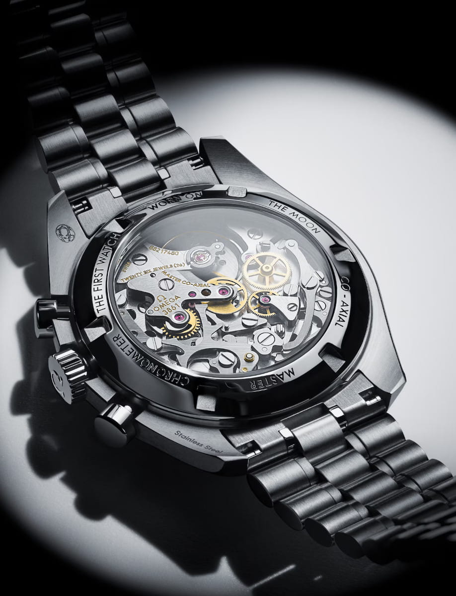 Stainless steel wristwatch with a transparent back showing intricate gears and jewels of the mechanical movement