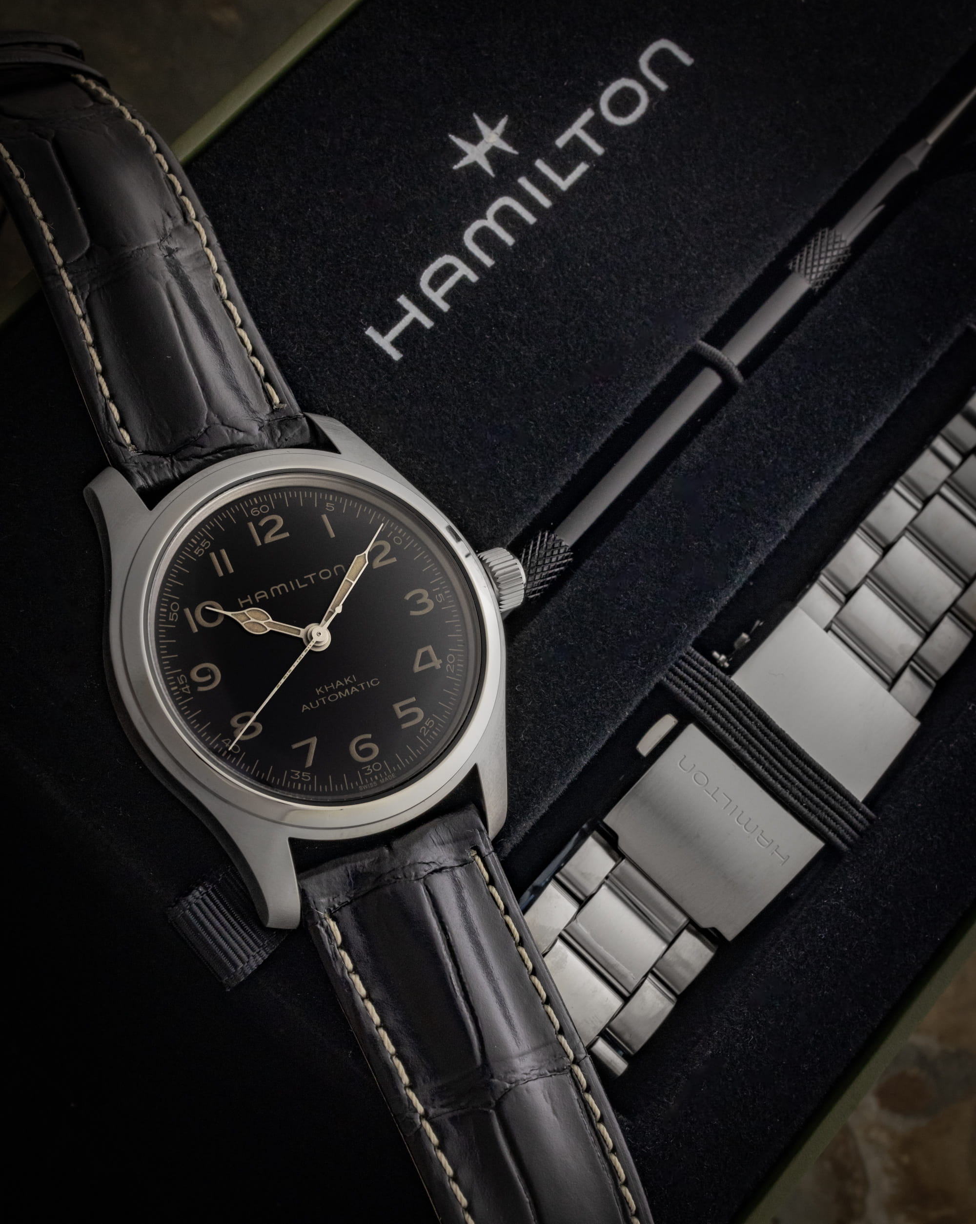 Hamilton wristwatch with stainless steel case, black dial, and black leather strap, and additional stainless steel bracelet.