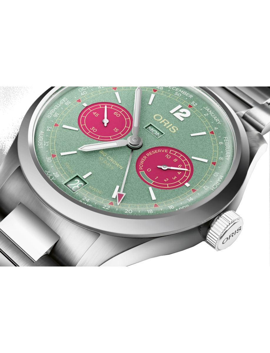 Close view of Oris wristwatch with stainless steel case and bracelet, and green dial with pink counters.