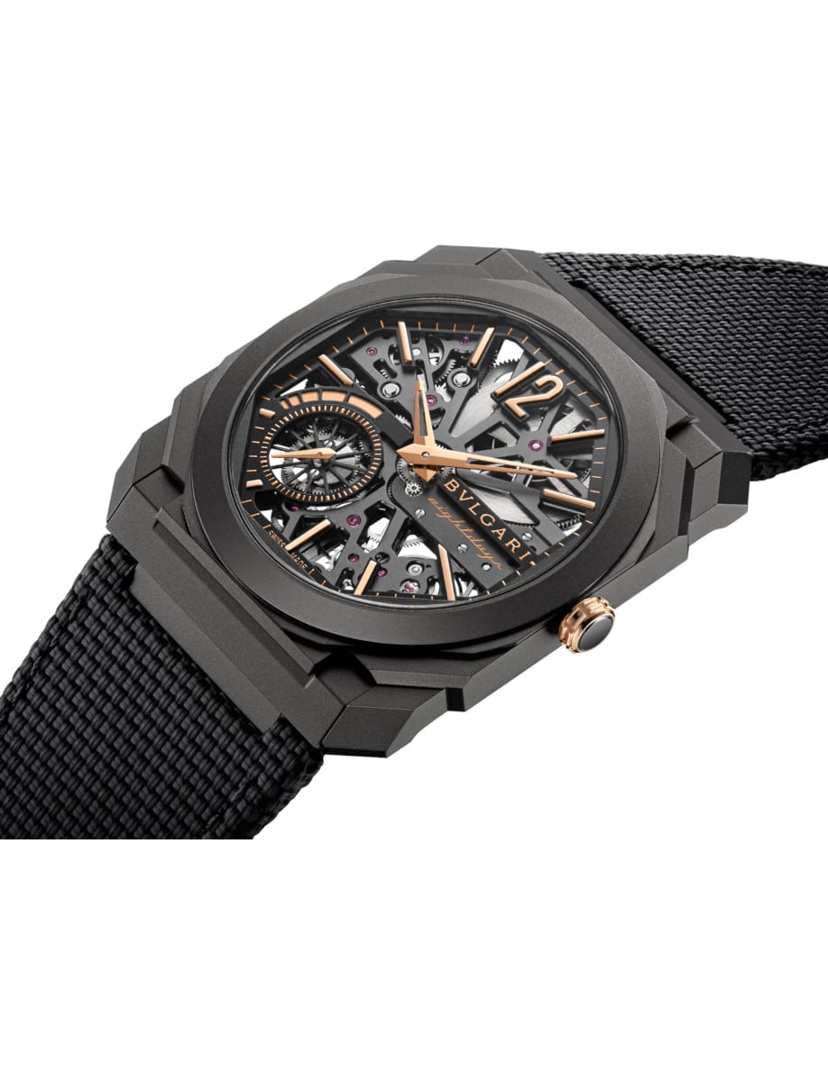 Side view of Bulgari wristwatch with black DLC-coated titanium case, openwork dial, and a black rubber bracelet.