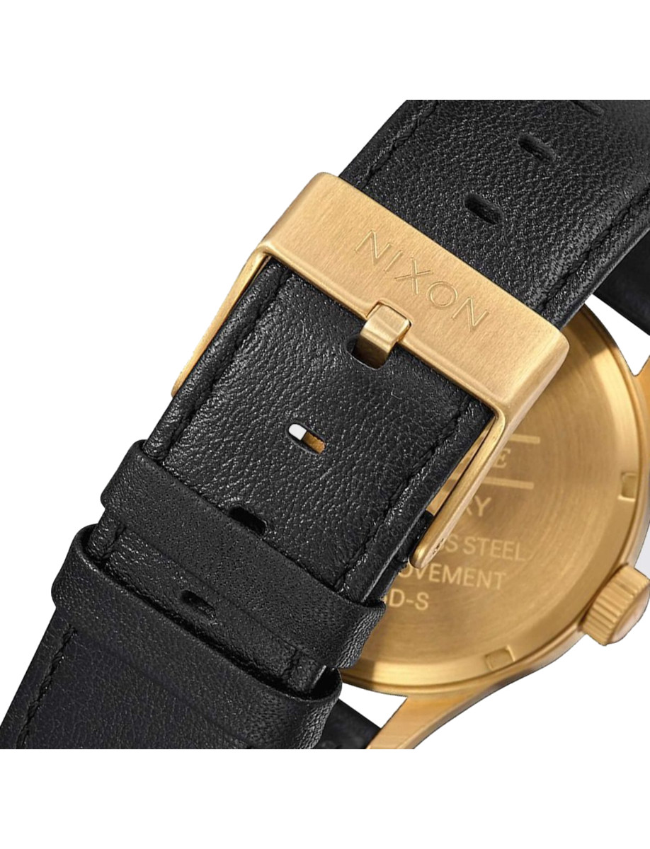 Black leather strap and gold-tone stainless steel buckle from Nixon wristwatch.