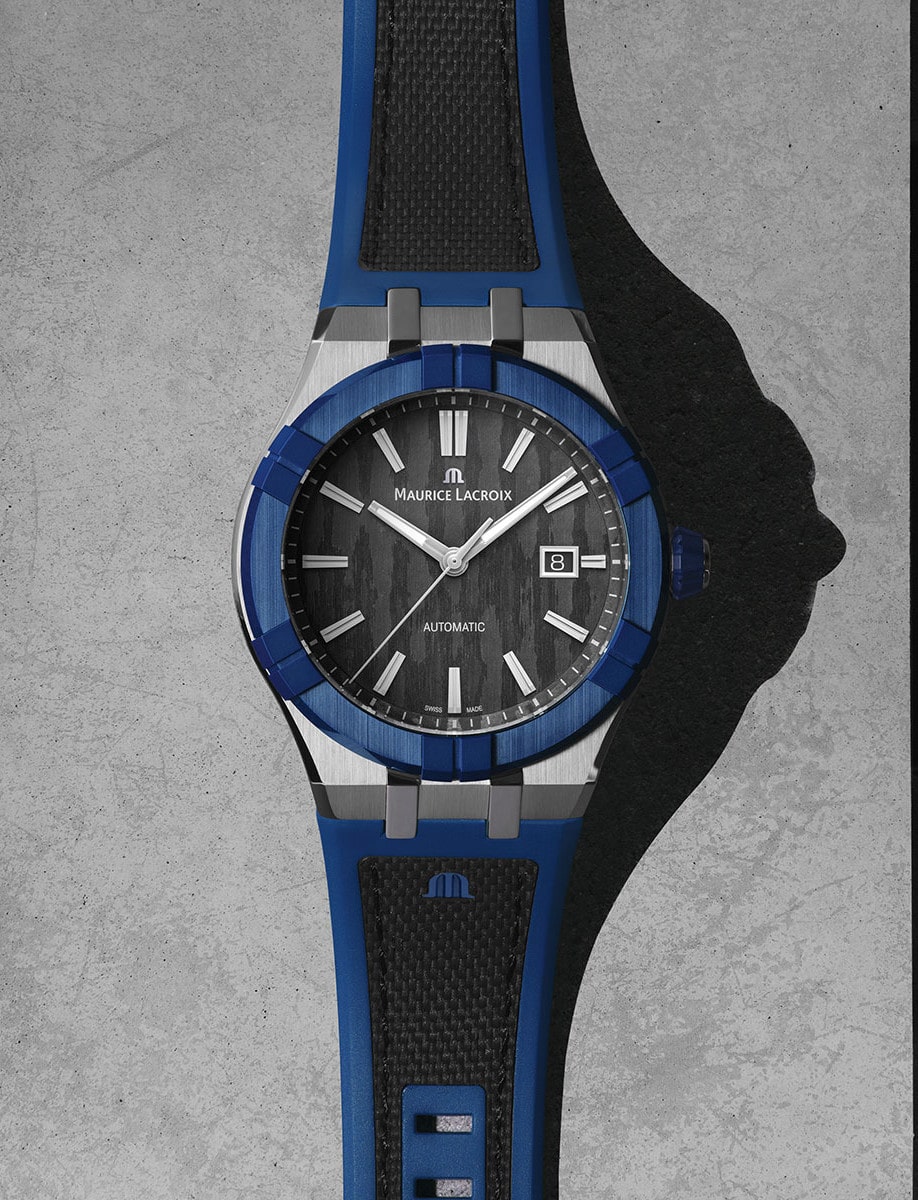Front view of Maurice Lacroix wristwatch with stainless steel case, blue bezel, bi-rubber strap, and a black dial.