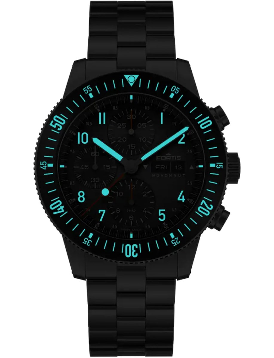 A wristwatch with a recycled stainless steel case and bracelet, shown at night with a luminous bezel, numerals, indexes, and hands.