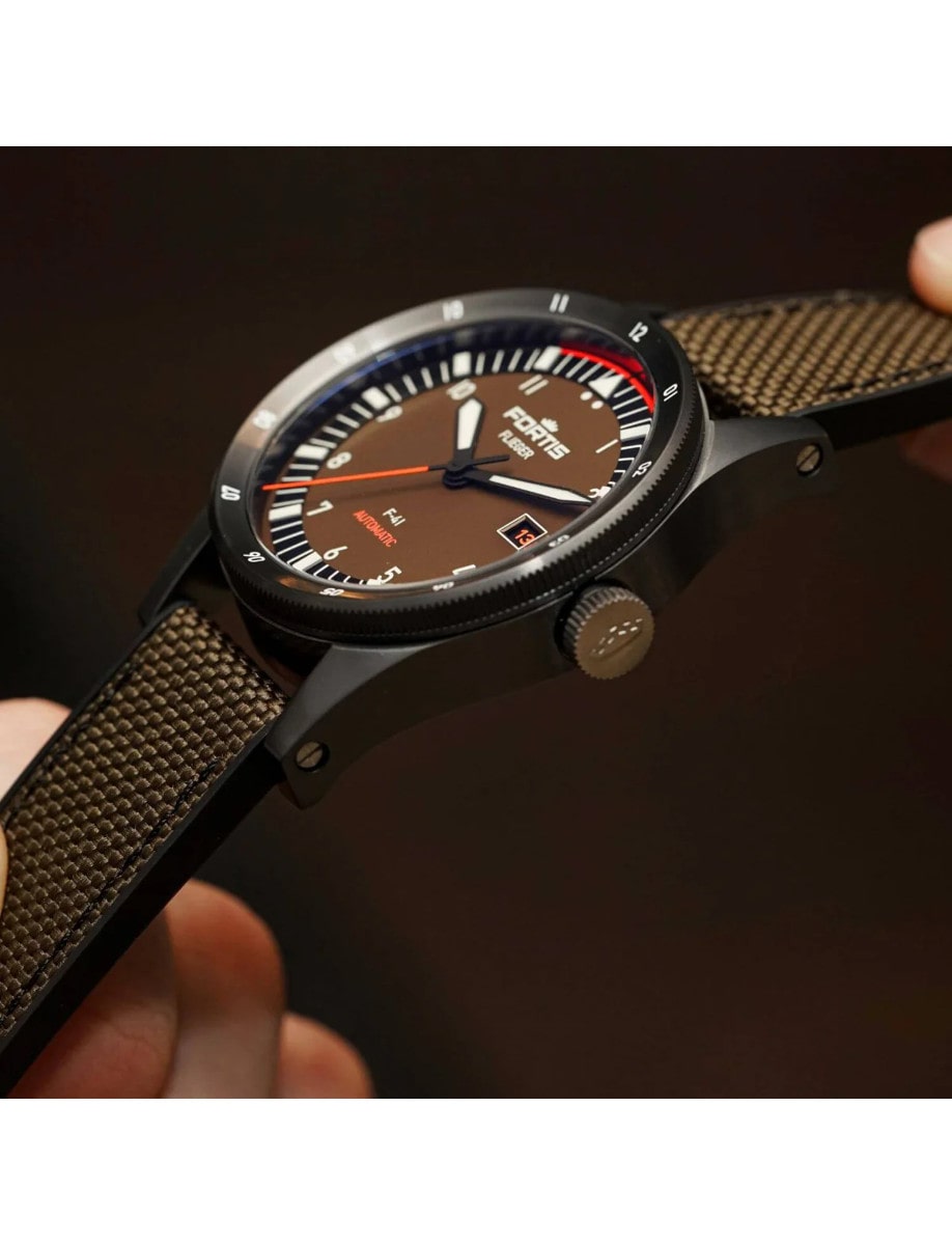 Side view of a wristwatch with a recycled stainless steel case coated in black DLC and a hybrid rubber/textile fabric strap, showing the side of the case and its crown.