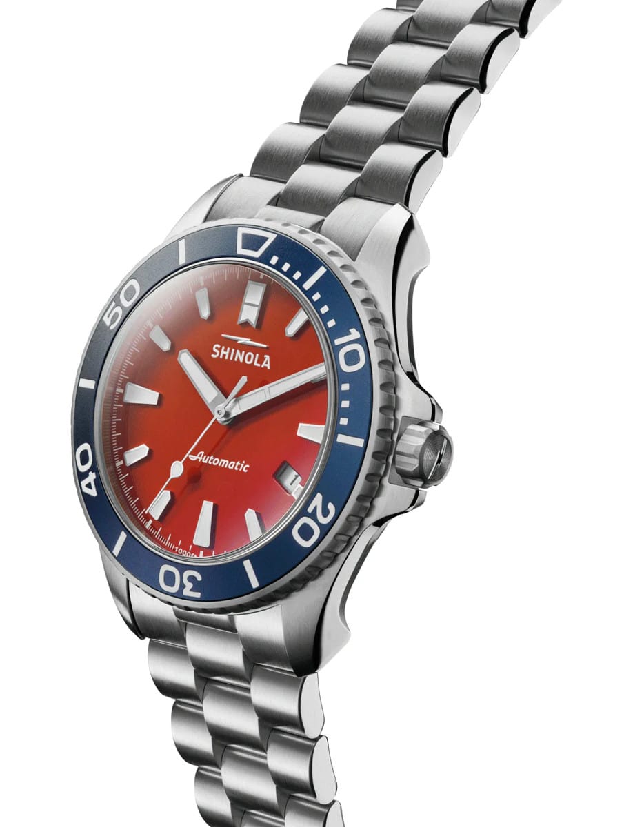 Side view of a Shinola wristwatch with stainless steel case and bracelet and red dial