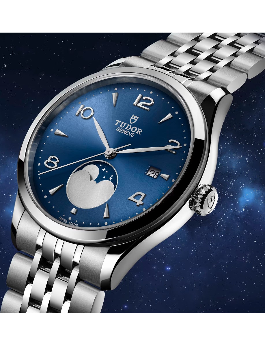 Side view of Tudor wristwatch with stainless steel case and bracelet, and blue satin sun-brushed dial with applied numerals and moon phase indicator.