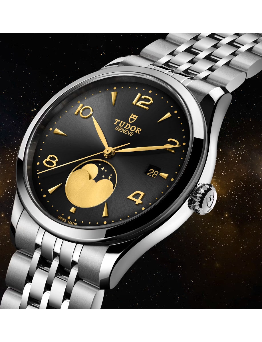 Side view of Tudor wristwatch with stainless steel case and bracelet, and black satin sun-brushed dial with applied numerals and moon phase indicator.