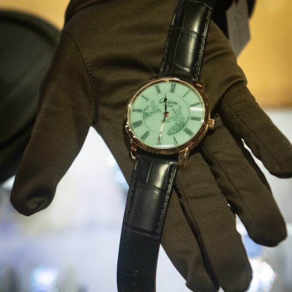 A gloved hand holding a watch from Glashutte Original over the counter at Feldmar's World Watch Day event