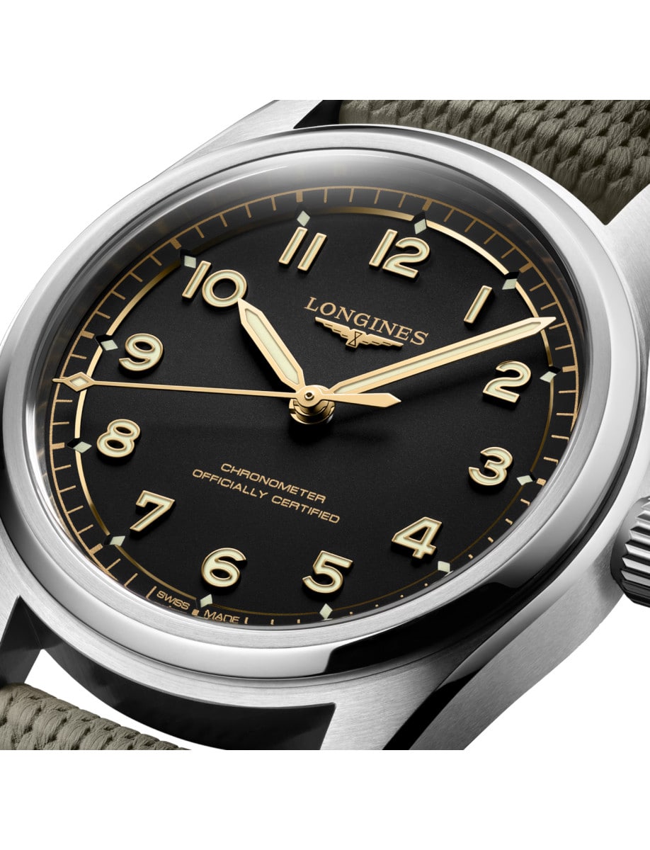 Close view of black dial of Longines wristwatch with stainless steel case, and green rubber strap.