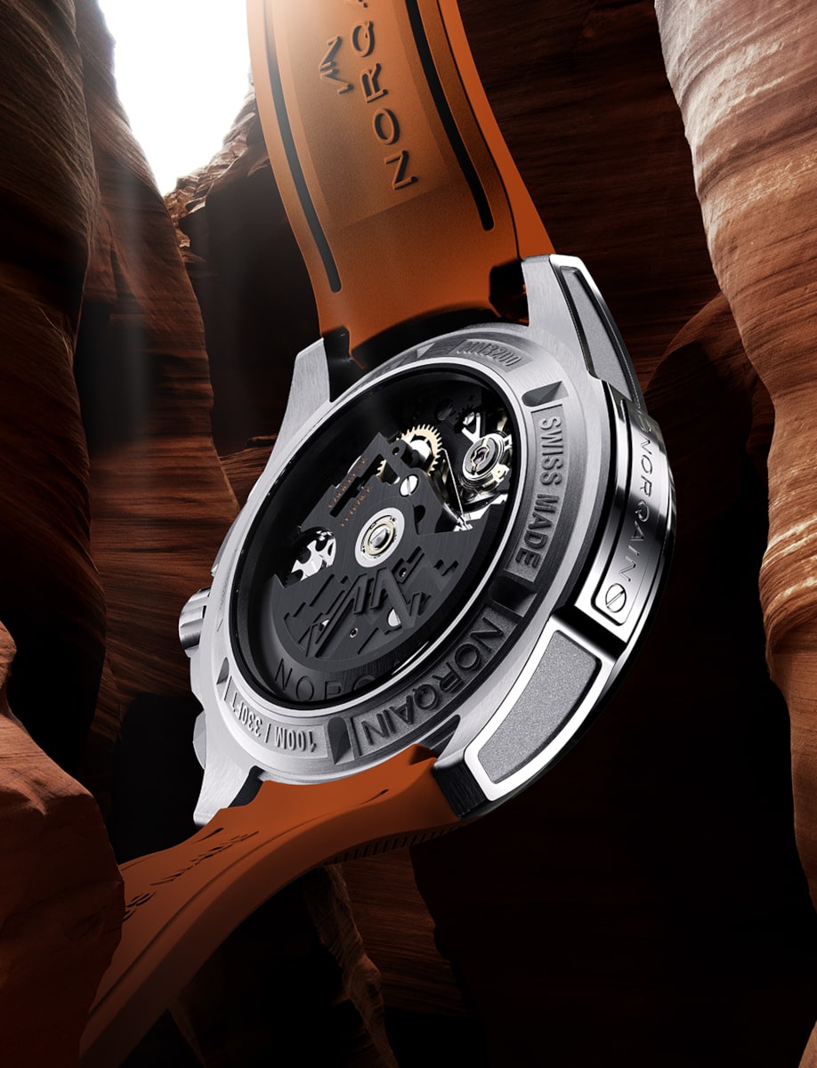 Back view of Norqain wristwatch with stainless steel case, skeleton orange dial, and transparent case back.