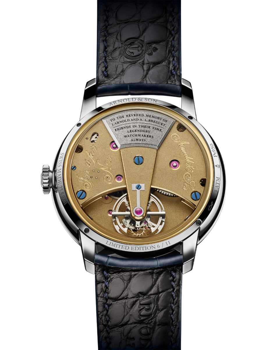 Back view of Arnold&Son wristwatch with platinum case, 18k yellow gold case back, and midnight blue alligator strap.