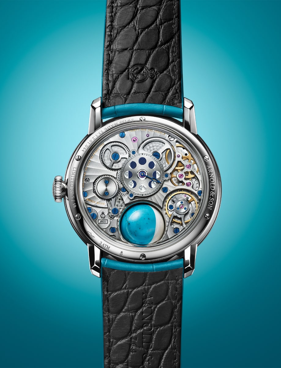 Back view of Arnold&Son wristwatch with stainless steel case, open case back, and turquoise alligator leather strap.