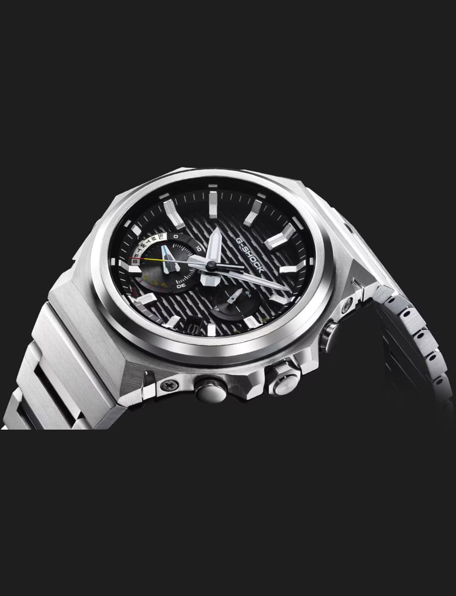 Side view of Seiko wristwatch with carbon and stainless steel case, black dial, and stainless steel bracelet.