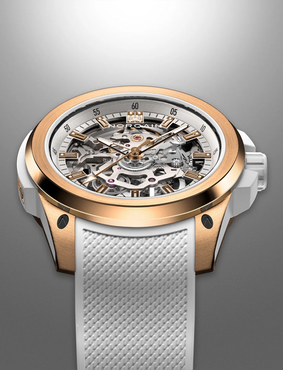 Front side view of Norqain wristwatch with red gold case, white rubber strap, and skeleton dial.