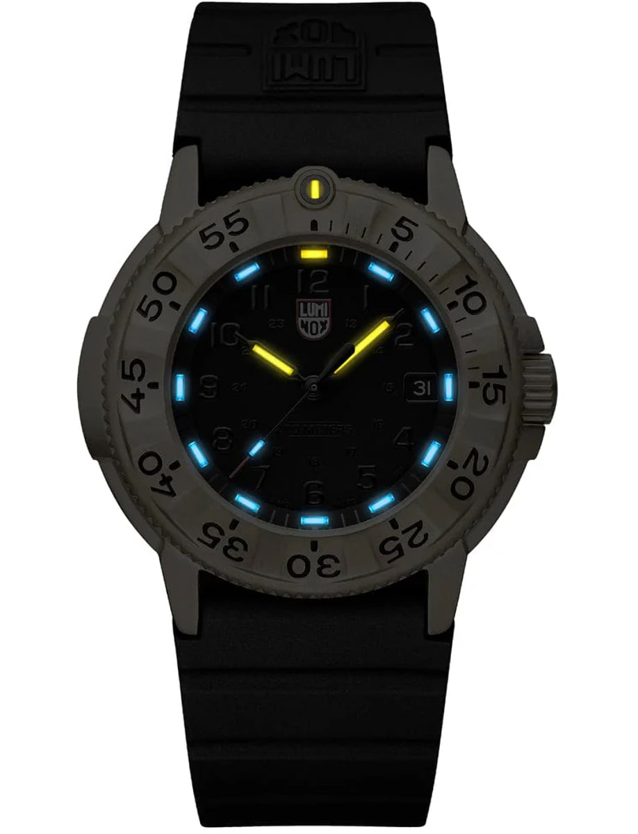 Night view of Luminox wristwatch with gold stainless steel case, black dial and black rubber strap