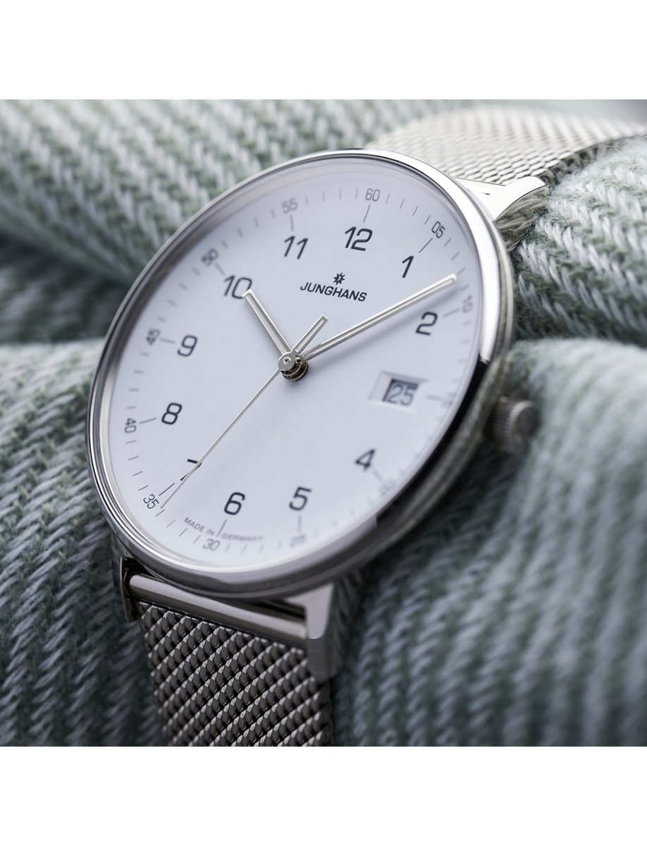 Side view of Junghans wristwatch with stainless steel case and milanese bracelet, and matt white dial.