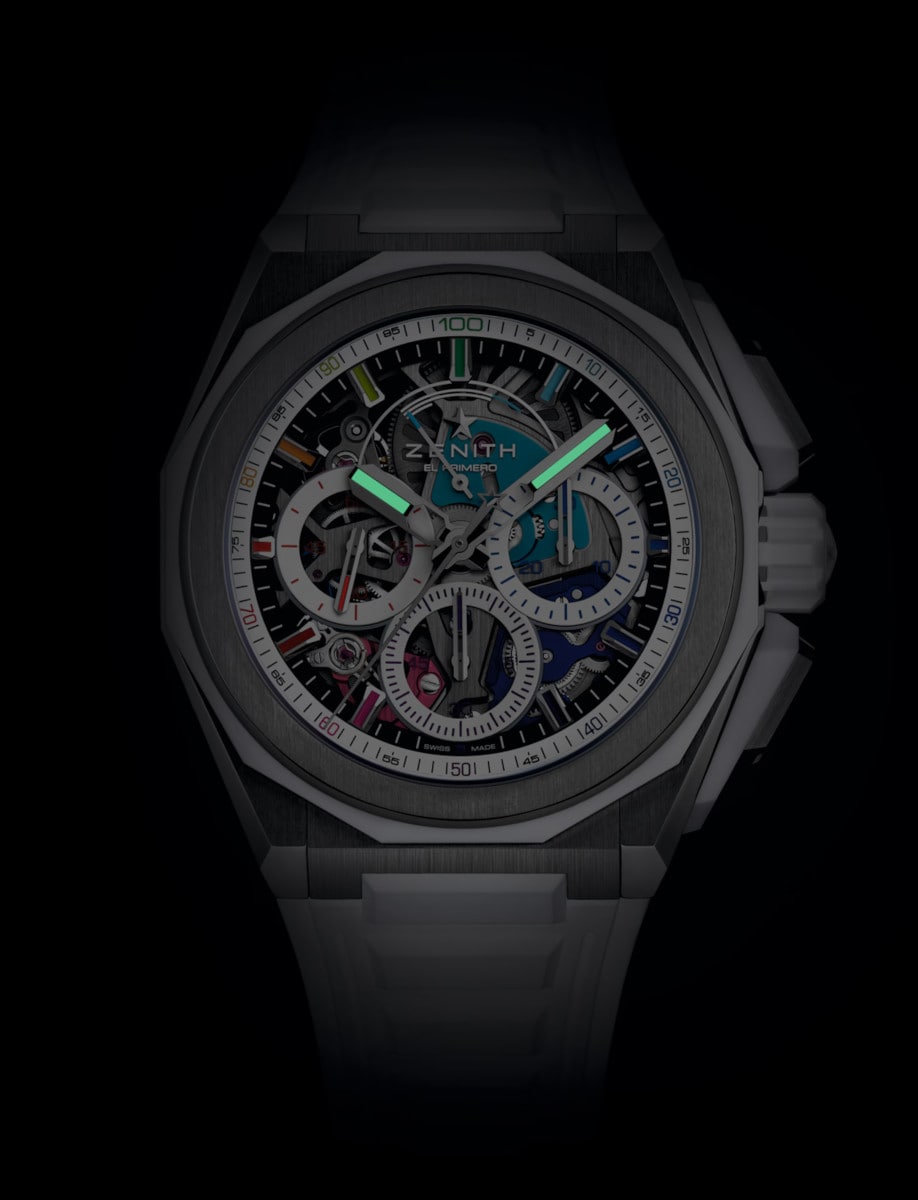 Night view of Zenith wristwatch with titanium case, multicolor sapphire dial, and white rubber strap with folding clasp.
