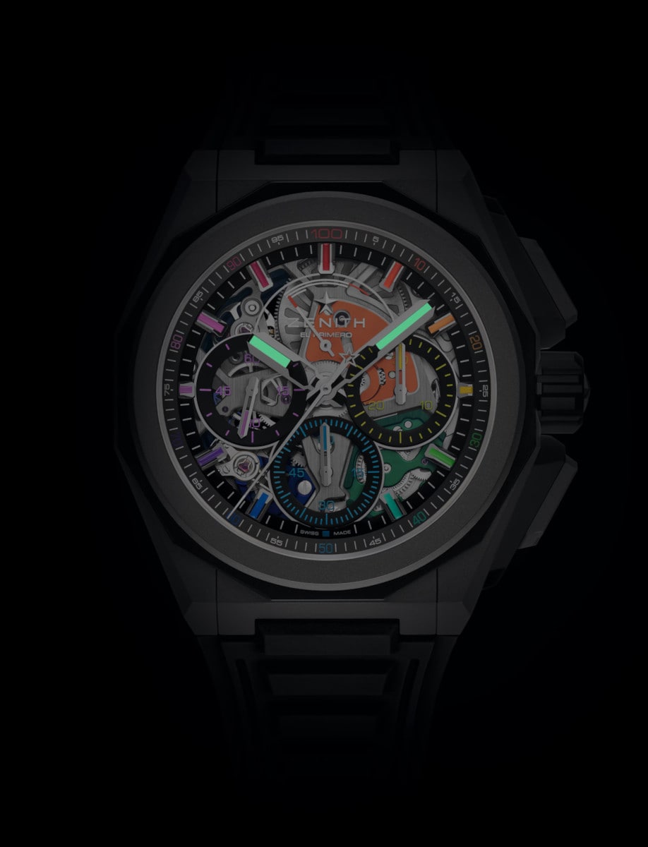 Night view of Zenith wristwatch with microblasted titanium case, multicolor sapphire dial, and black rubber strap with folding clasp.