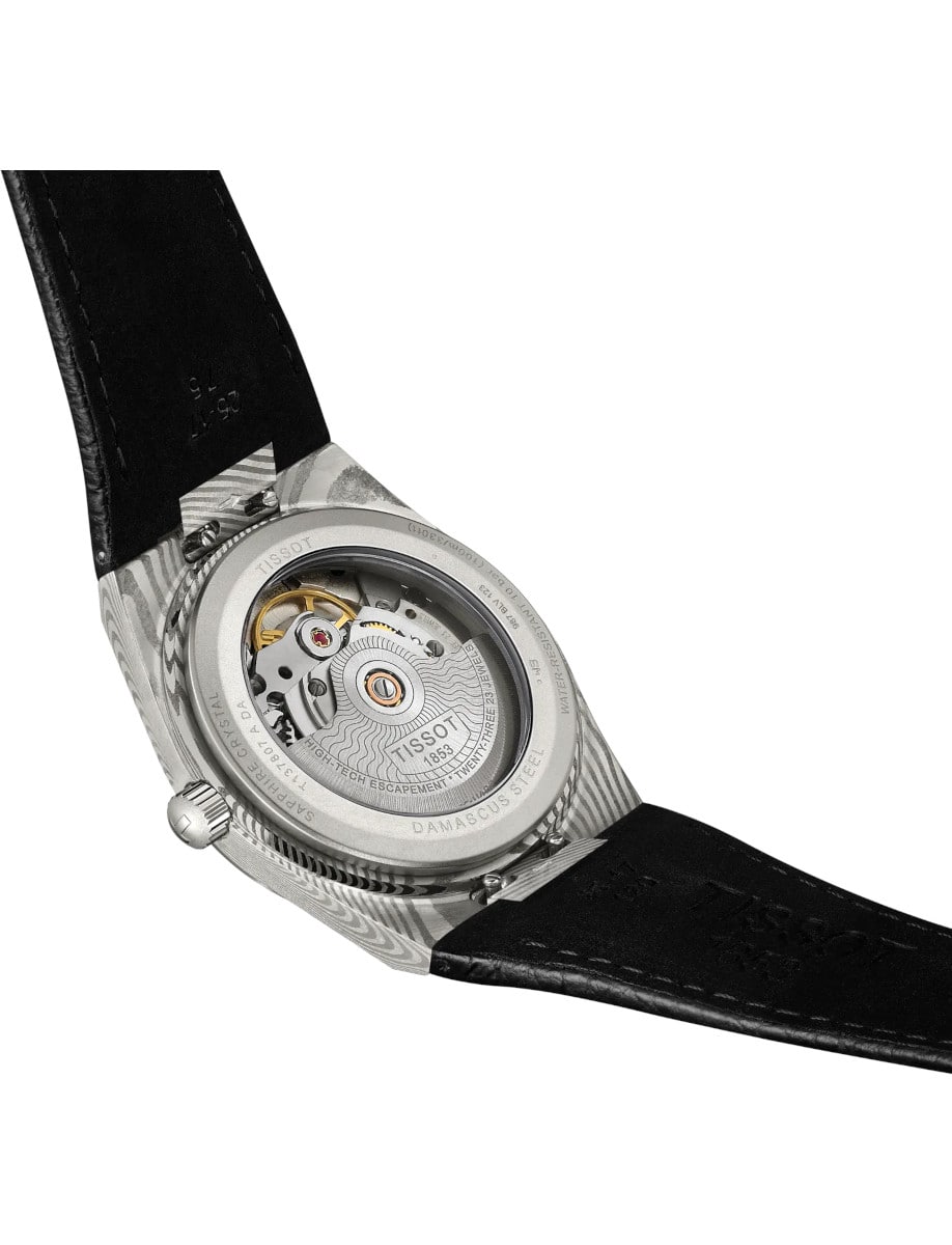 Back view of Tissot wristwatch with Marbled Damascus stainless steel case, open case back, and black embossed cow leather strap.