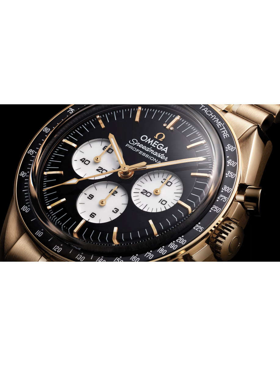 Close-up of a gold Omega Speedmaster Professional wristwatch with a black dial and white subdials on a tachymeter bezel.