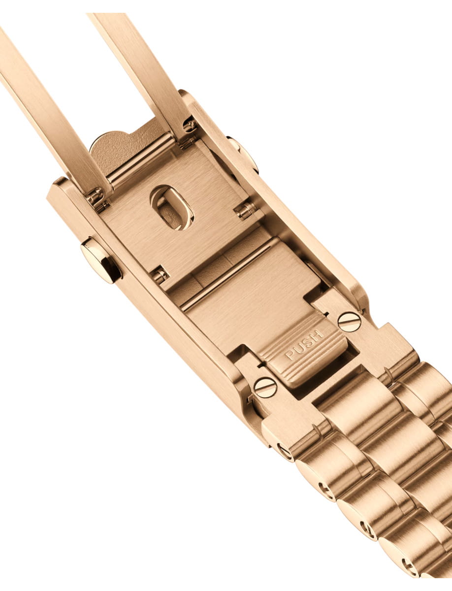 Gold metal watch band clasp with a push-release button, showing the hinge and links on a luxury bracelet