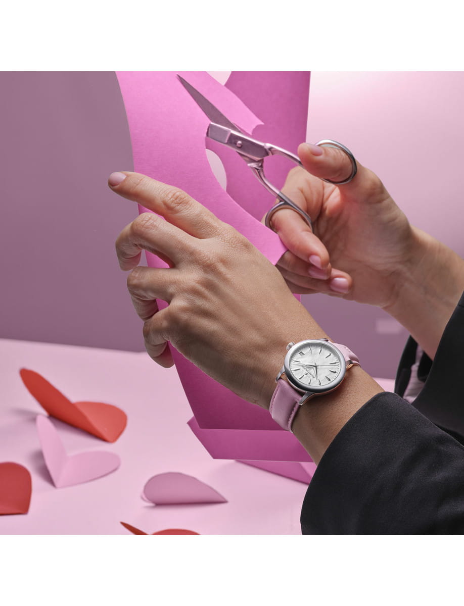 An image of wearing Maurice Lacroix 1975 wristwatch with stainless steel case, pink mother-of-pearl dial, and pink leather strap.