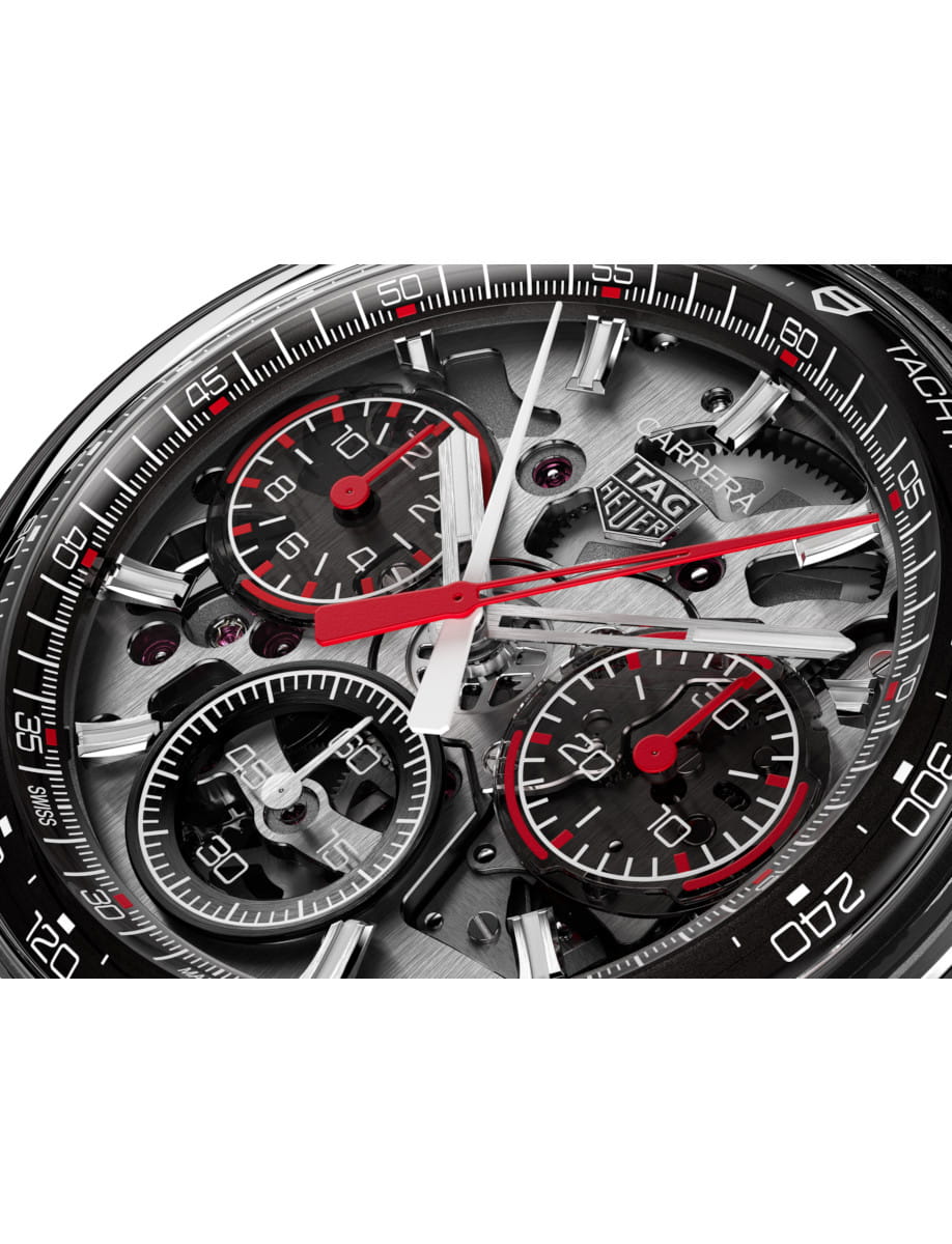 Close view of Tag Heuer wristwatch with stainless steel case, transparent dial, and black rubber and leather strap.