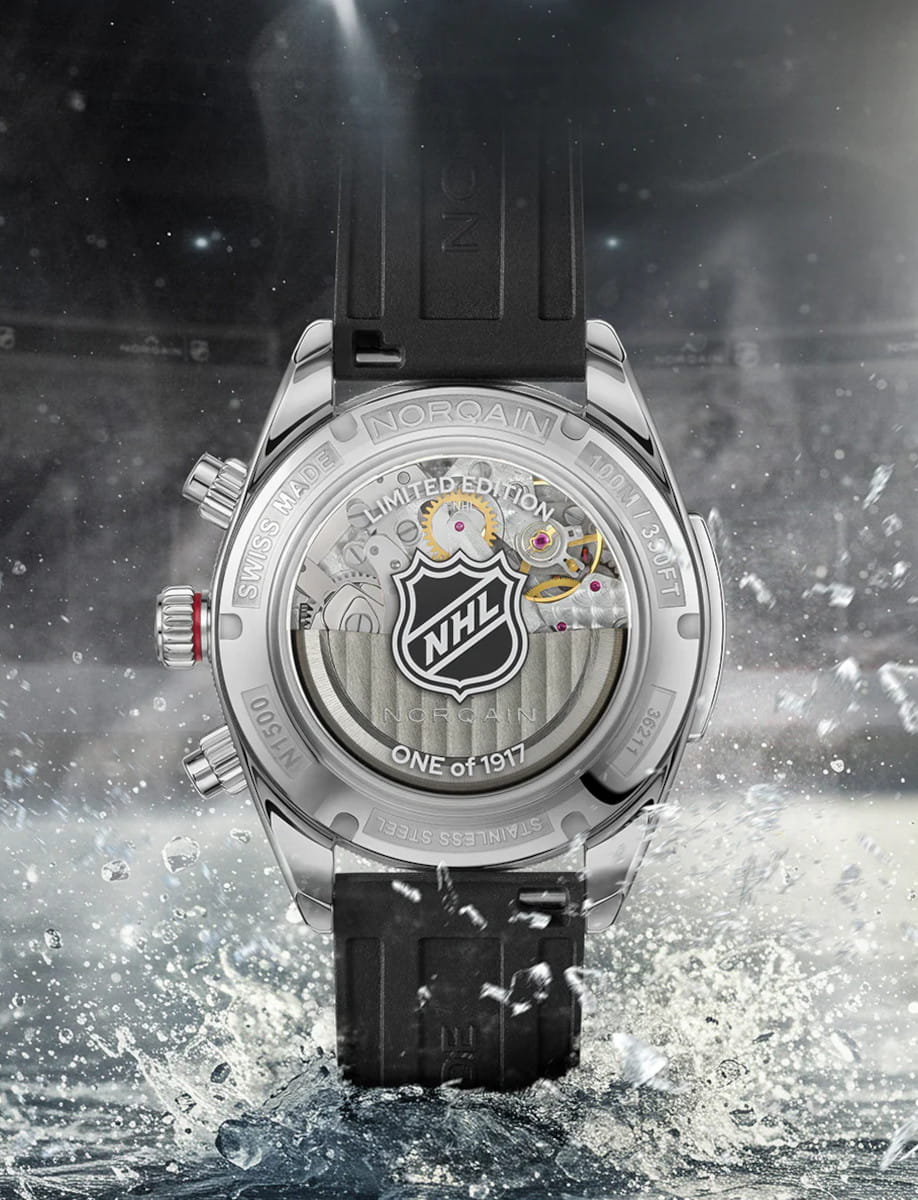 Back view of Norqain wristwatch with stainless steel case, white dial with black counters, and black NHL puck rubber strap.