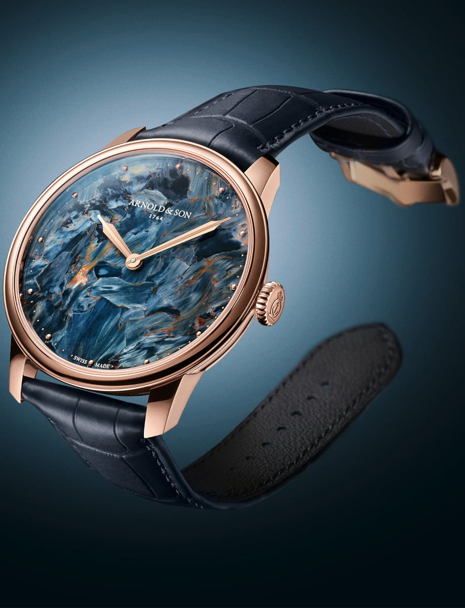 Side view of Arnold&Son HM Pietersite wristwatch with 18k red gold case, Namibian pietersite dial, and ink blue alligator leather strap.