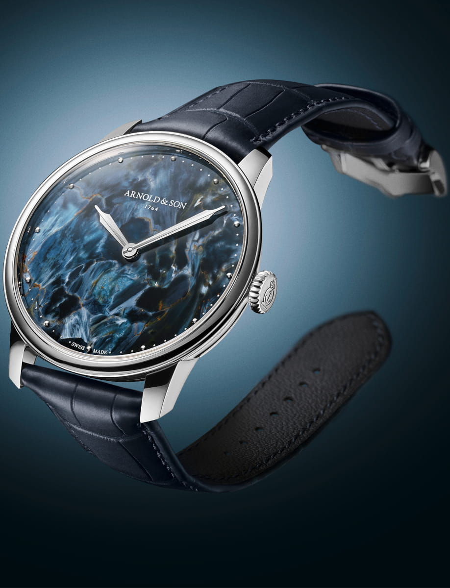 Side view of Arnold&Son HM Pietersite wristwatch with stainless steel case, Namibian pietersite dial, and ink blue alligator leather strap.