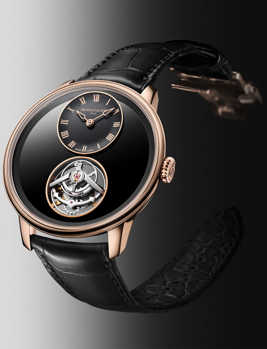 Side view of Arnold&Son wristwatch with 5n red gold case, black dial, and black leather strap.