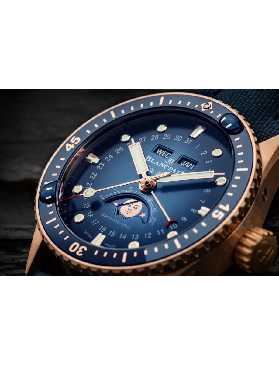 Side view of Blancpain Bathyscaphe Quantième Complet Phases de Lune wristwatch with red gold case, sunburst blue with subtly graduated coloring dial, and blue sail-canvas strap.