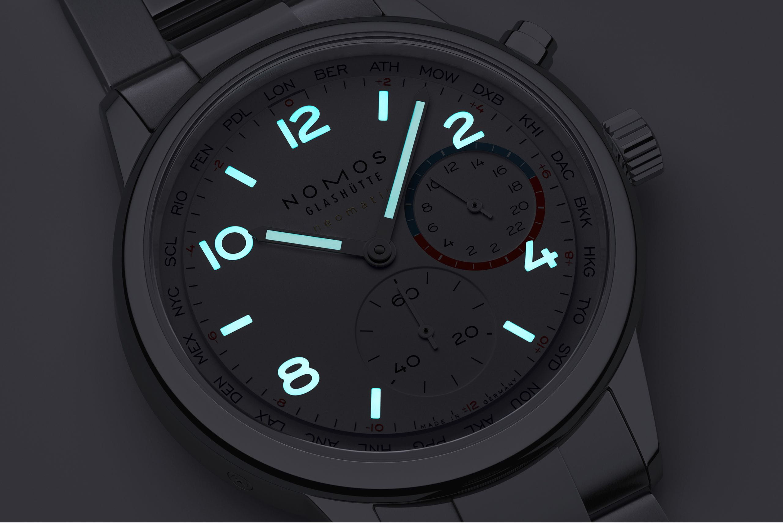 Nomos Club Sport neomatik Worldtimer wristwatch with stainless steel case and bracelet, and white dial with luminous hands and numerals.