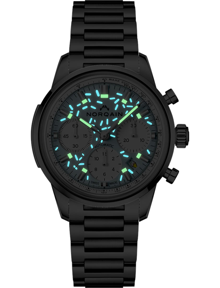 Night view of Norqain Sprinkles Blue Raspberry wristwatch with stainless steel case and bracelet, and light blue dial.