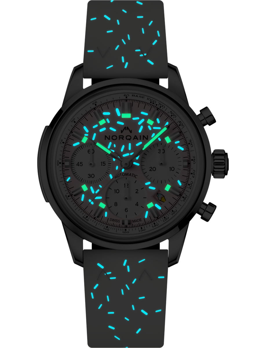 Night view of Norqain Strawberry wristwatch with stainless steel case, light pink dial, and blue rubber strap.