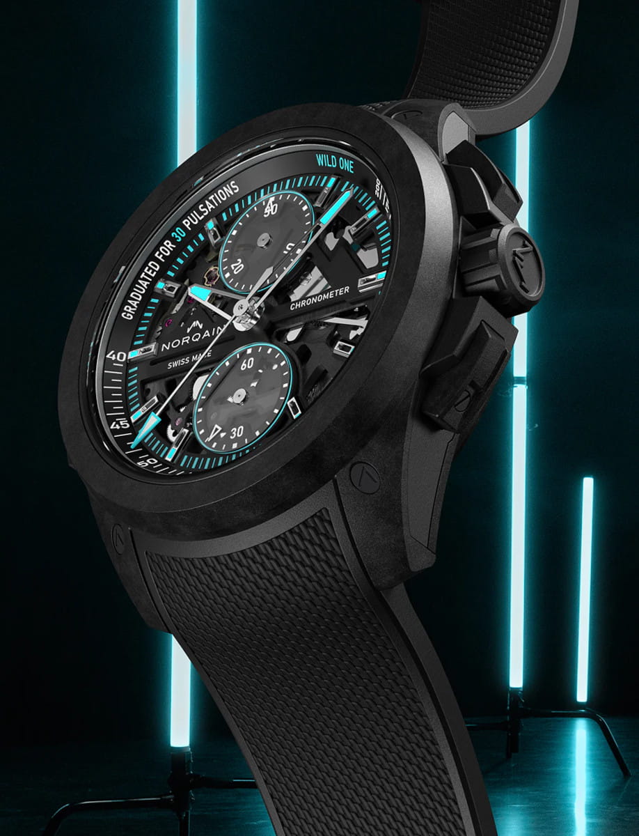 Left side view of Norqain Wild ONE Skeleton Chrono wristwatch with NORTEQ titanium case, black dial with white and turquoise printings, black rubber strap with “Milanese” pattern.