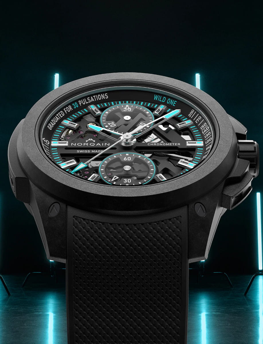 Front side view of Norqain Wild ONE Skeleton Chrono wristwatch with NORTEQ titanium case, black dial with white and turquoise printings, black rubber strap with “Milanese” pattern.