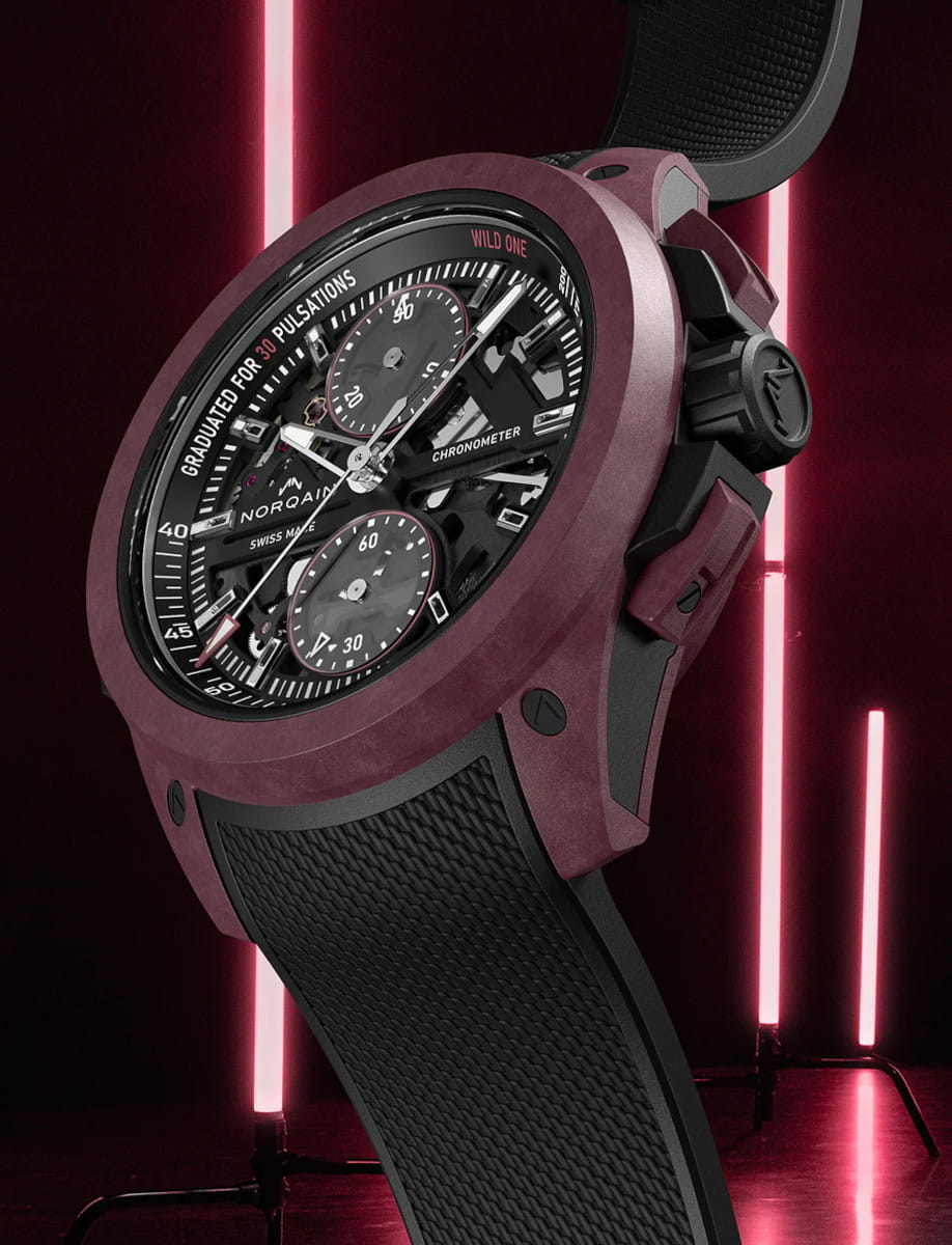 Left side view of Norqain Wild ONE Skeleton Chrono wristwatch with Burgundy NORTEQ titanium case, black dial with white and burgundy printings, black rubber strap with “Milanese” pattern.