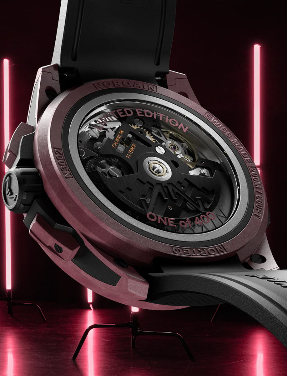 Back side view of Norqain Wild ONE Skeleton Chrono wristwatch with Burgundy NORTEQ titanium case, transparent caseback, black rubber strap with “Milanese” pattern.