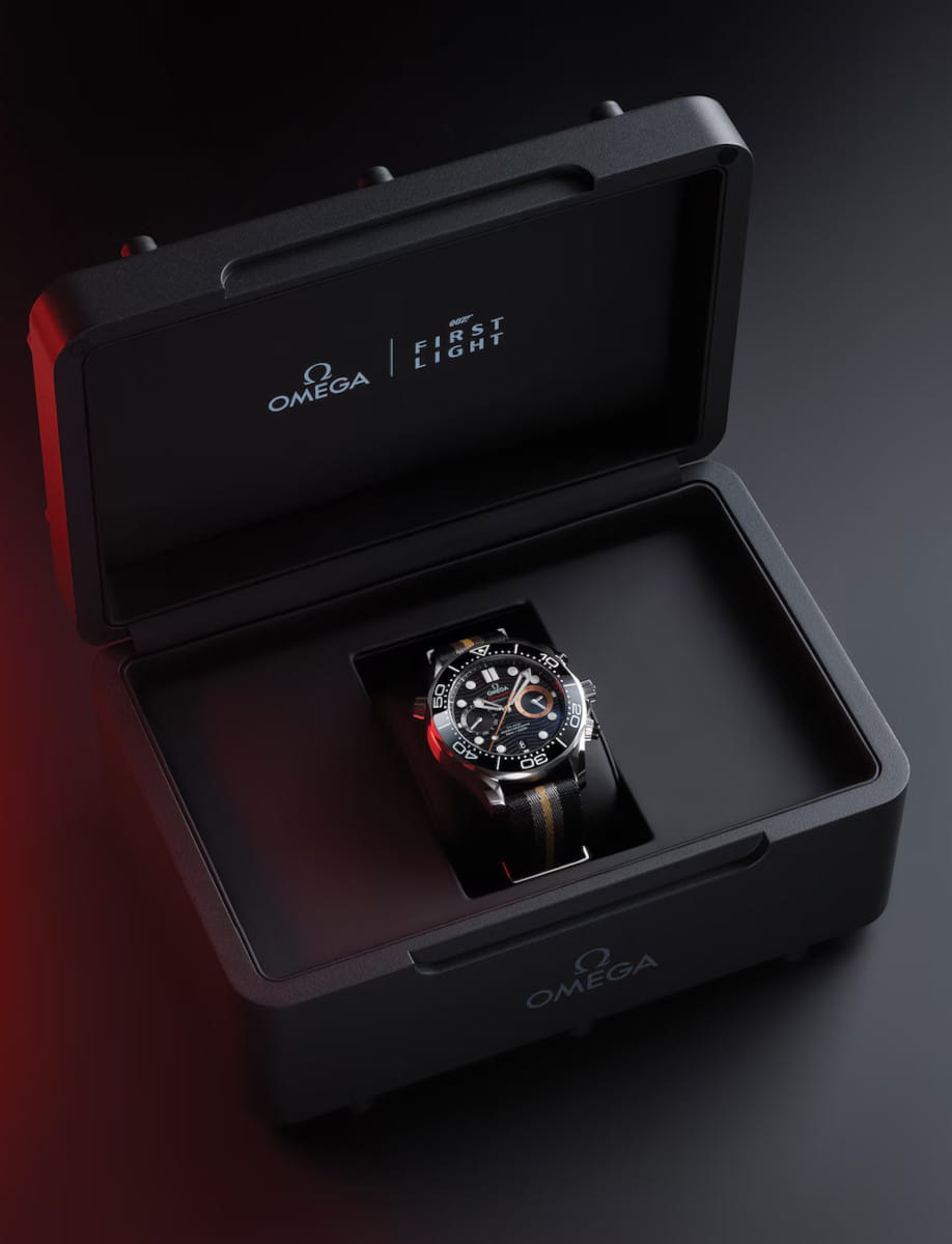 Box view of Omega wristwatch with stainless steel case, black dial, and NATO strap