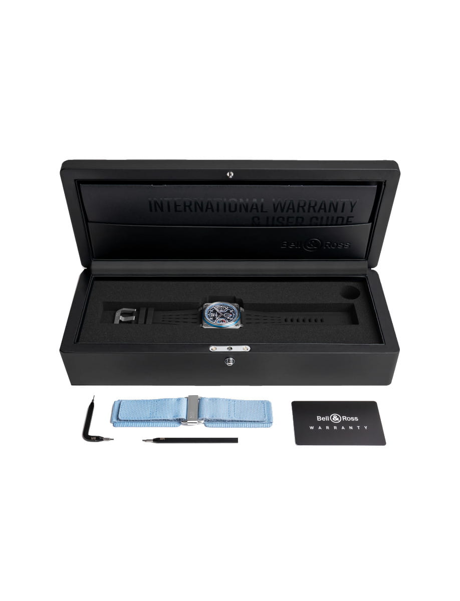 Box view of Bell&Ross BR-X3 Patrouille de France wristwatch with stainless steel case, black rubber strap and additional blue synthetic fabric strap, and matt black base dial with blue and white skeletonised applique.