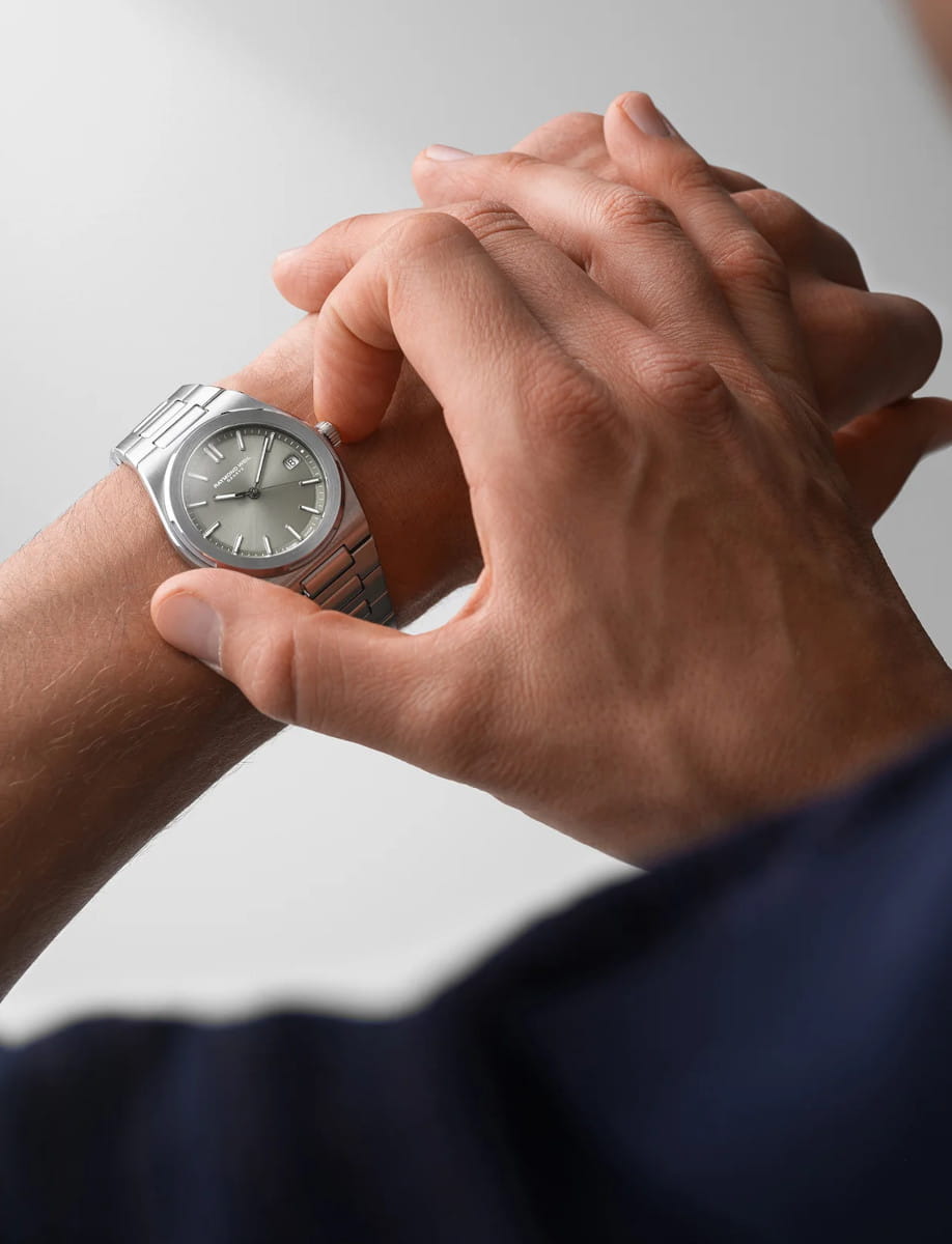 Lifestyle image of Raymond Weil A.R.T. wristwatch with stainless steel case and bracelet, and sage green dial.