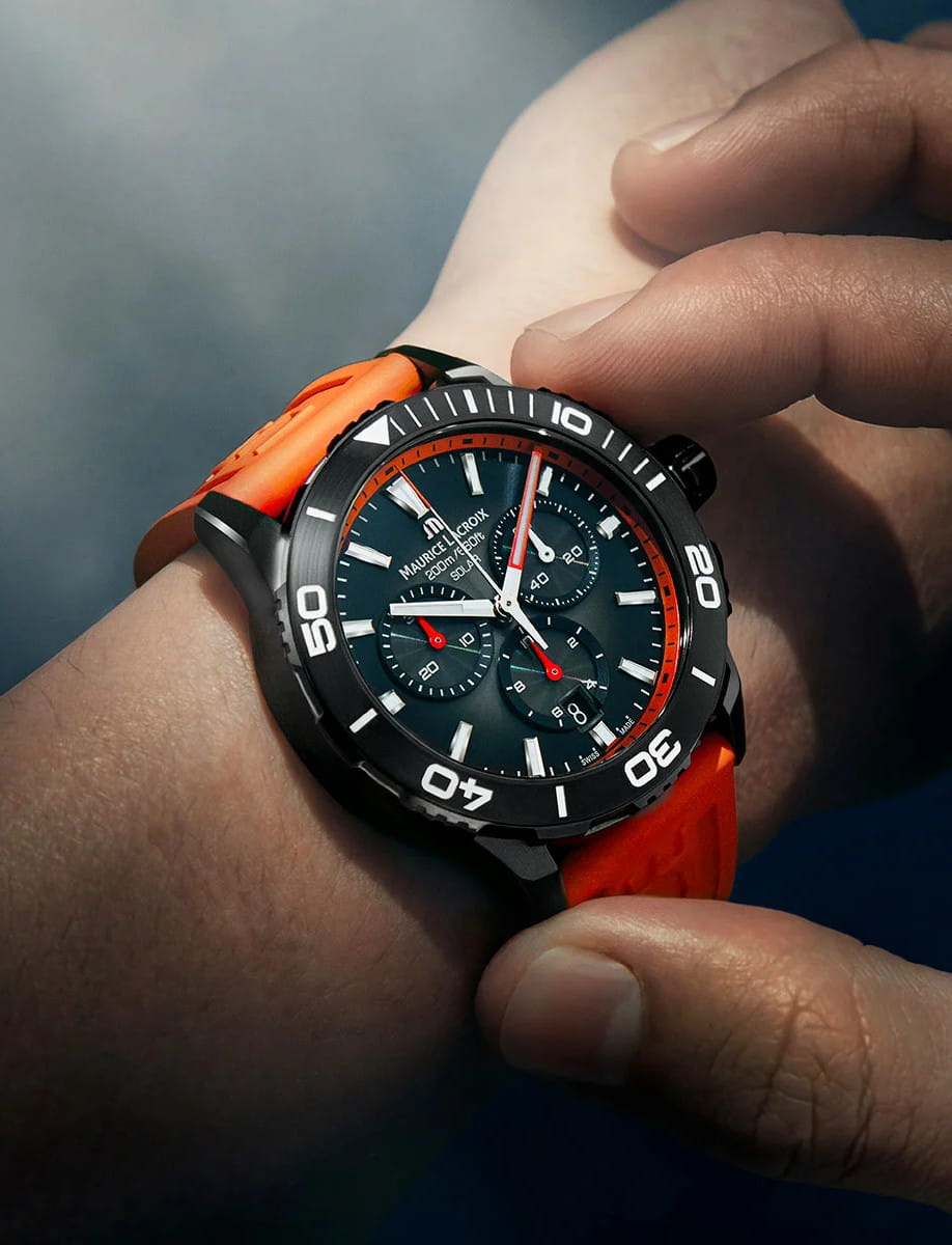 Lifestyle view of Maurice Lacroix Pontos S Solar Chronograph wristwatch with stainless steel case with Gun DLC coating, black smoked translucid dial, and orange fluo rubber FKM strap with Maurice Lacroix debossed.