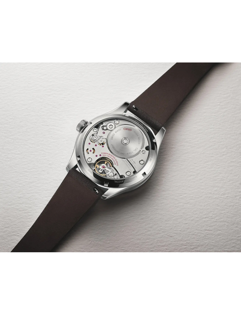 Back of a silver mechanical wristwatch with a brown leather strap, showing the gears through a transparent case.
