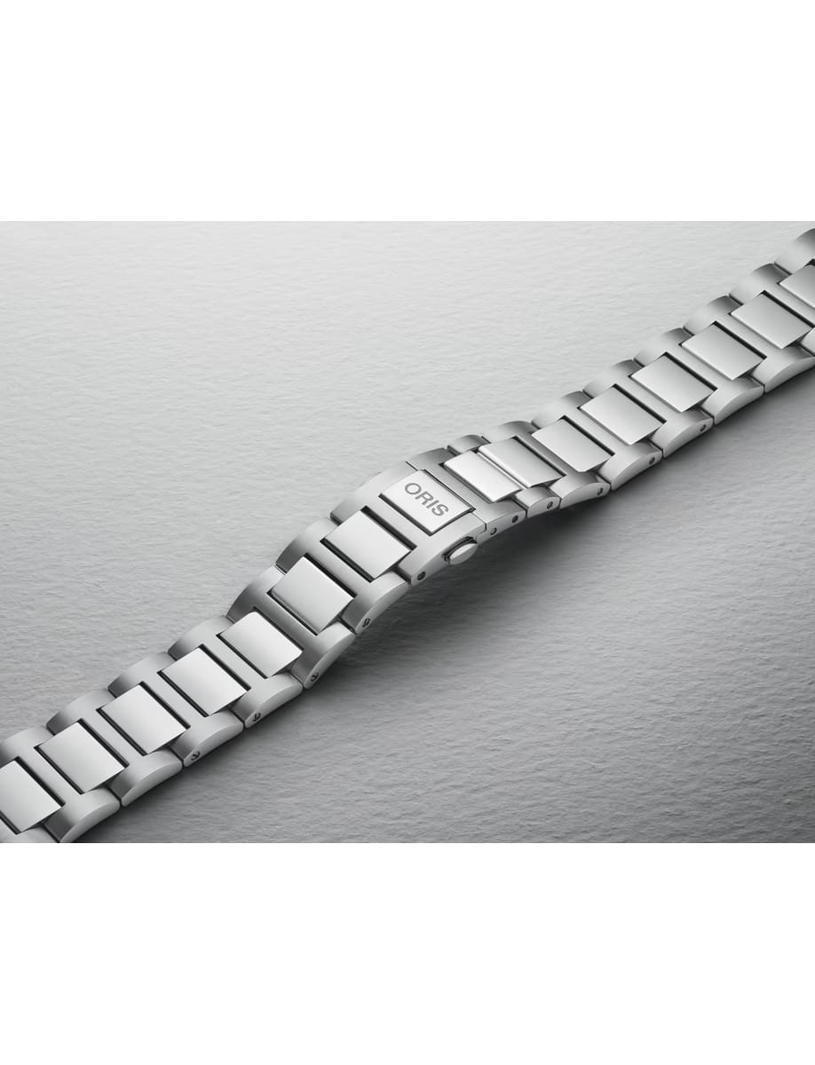 Close-up of a silver metal watch bracelet with a clasp labeled 'ORIS' on a textured gray surface.