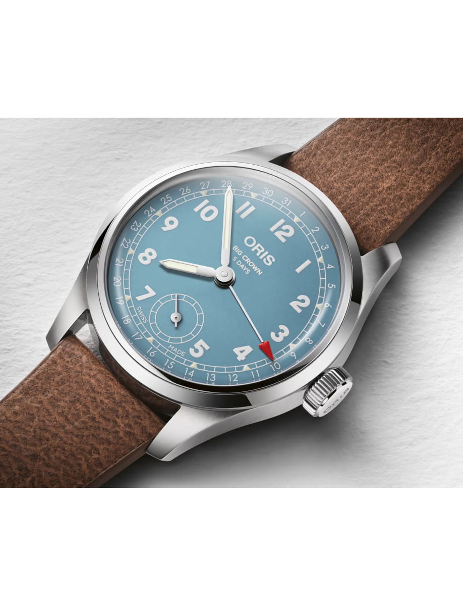 Blue dial Oris Big Crown wristwatch with white numerals and a brown leather strap, shown in close-up.
